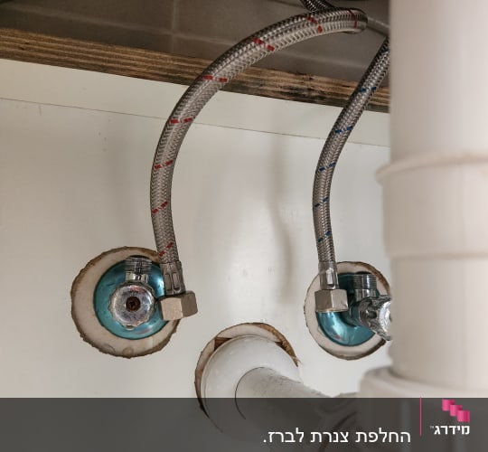 צינורות מתכת מחוברים לברזים מתחת לכיור